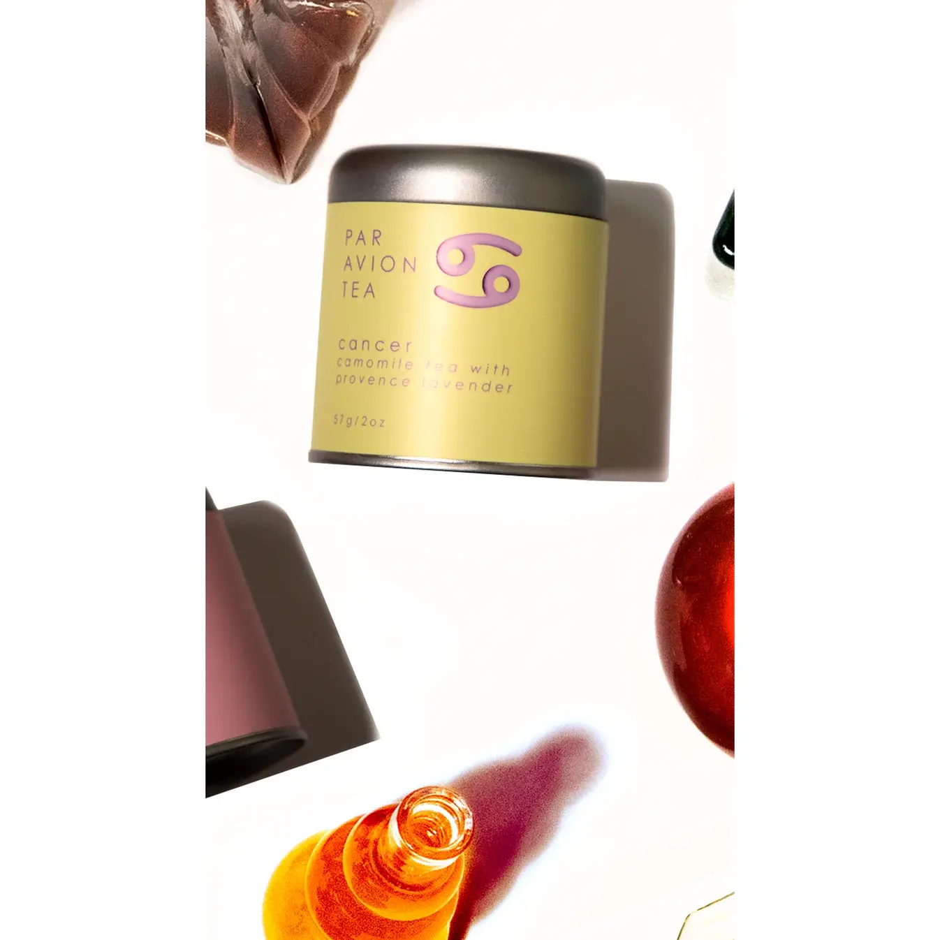 Flat lay of Cancer Luxury Zodiac Tea canister styled with other zodiac blends and a glass of brewed tea