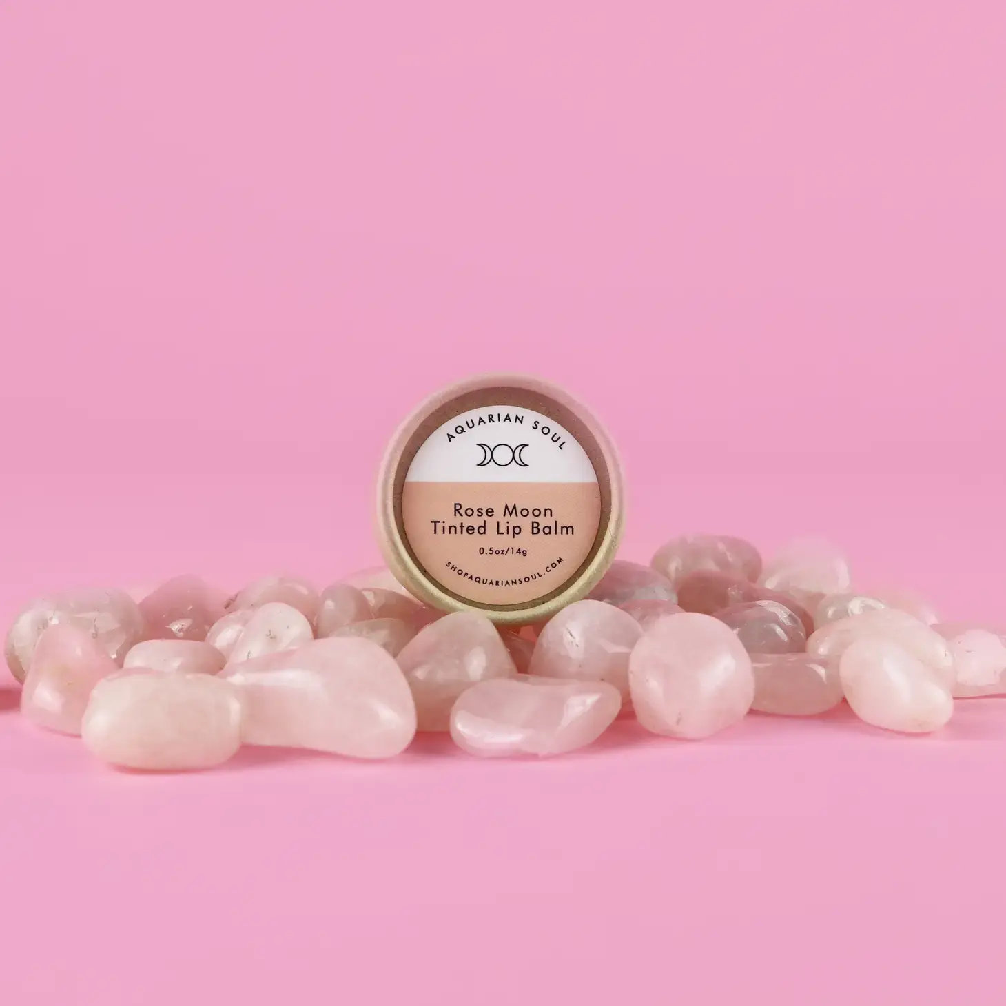 Rose Moon Tinted Lip Balm paired with polished rose quartz crystals – romantic, natural lip care on pink background