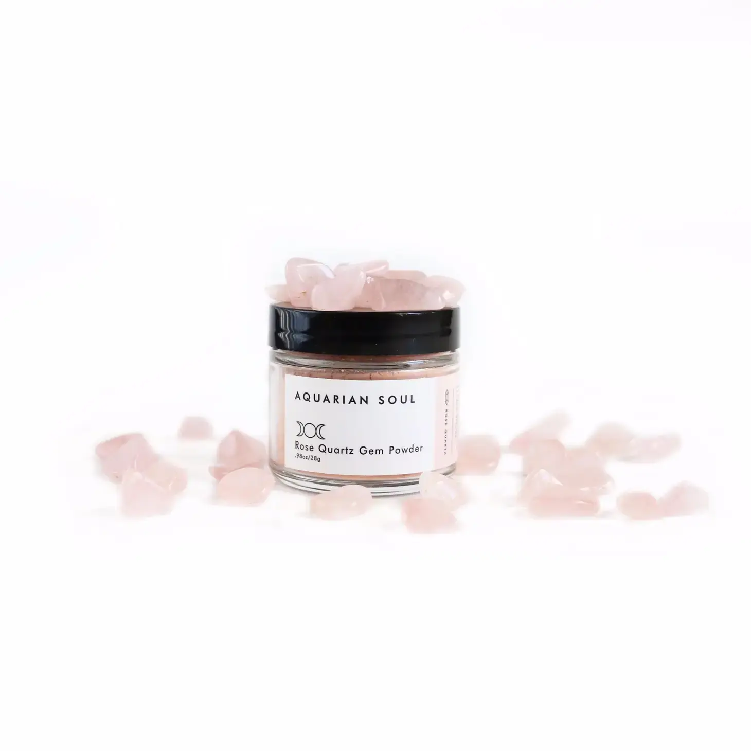 Closed jar of Rose Quartz Gem Powder Clay Mask surrounded by small rose quartz crystals on a white background
