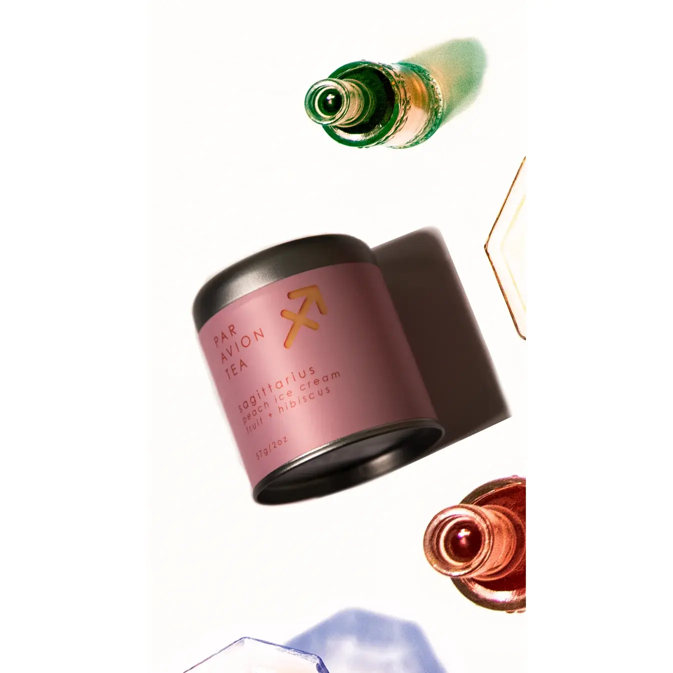 Flat lay of Sagittarius Luxury Zodiac Tea canister styled with other zodiac blends and a glass of brewed tea