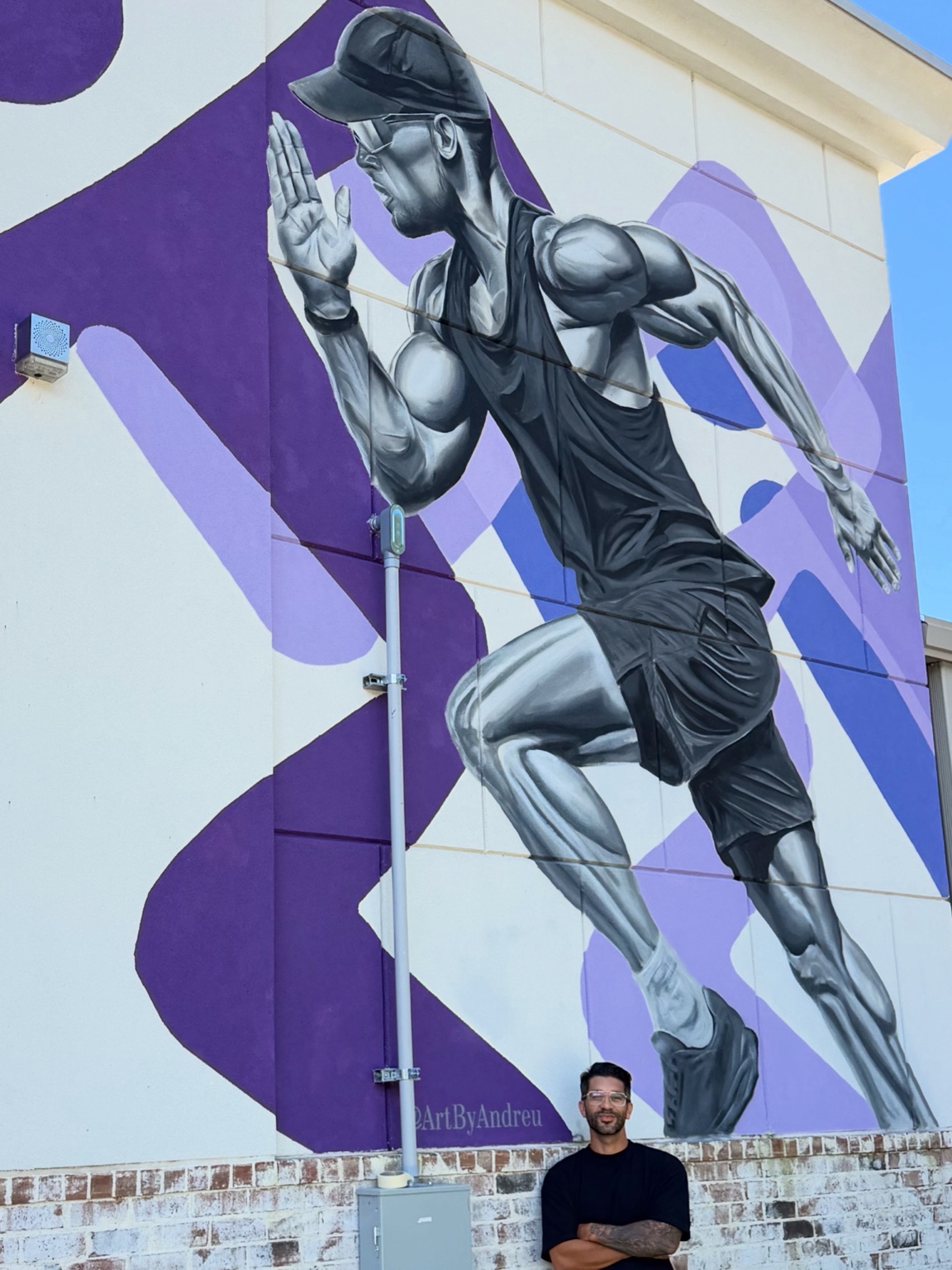 Closer view of the detailed running figure and artist in front of the Anytime Fitness mural
