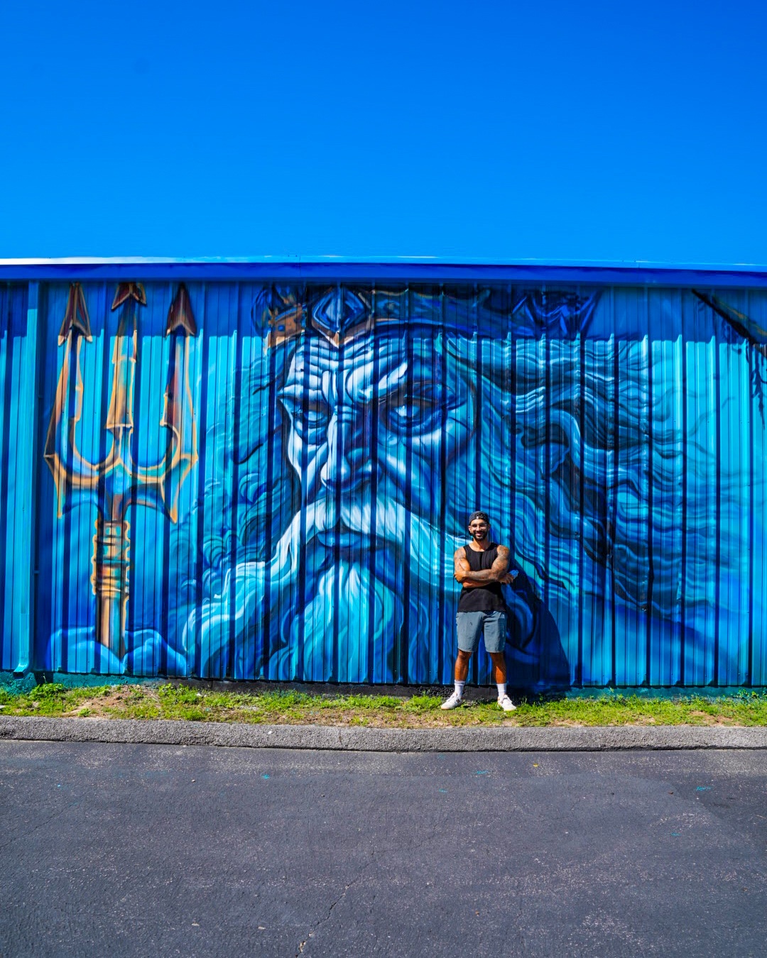 Large-scale blue Poseidon exterior mural for MBT Divers on a commercial building in Pensacola Florida