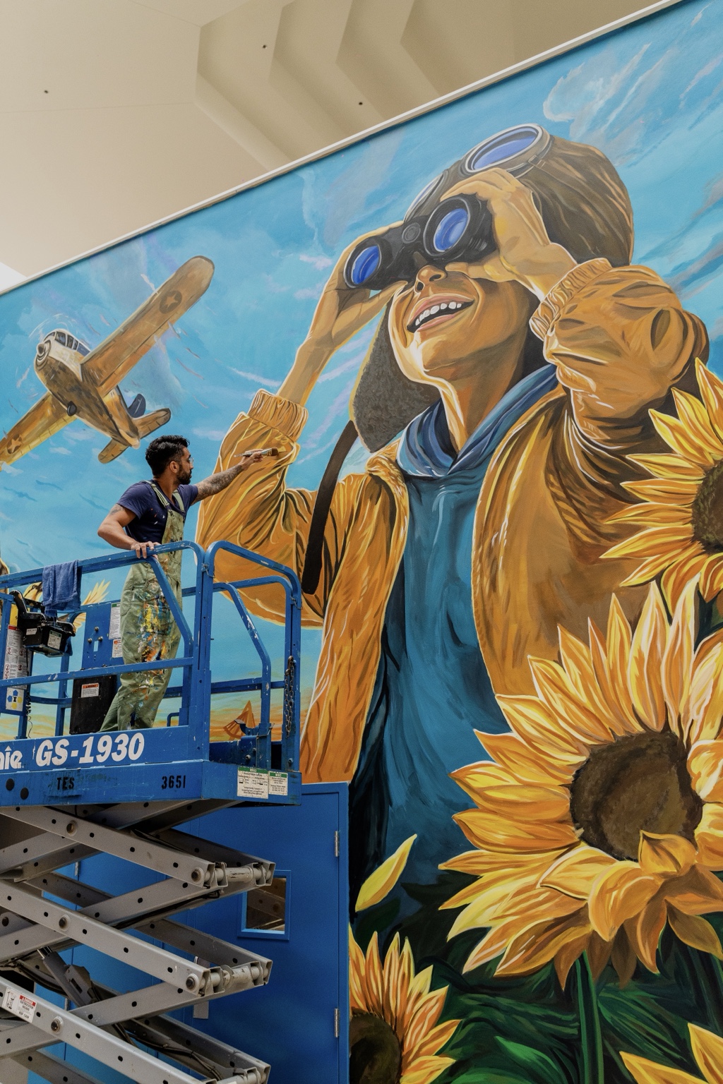 Close-up angled view of the Towne East Square mural with aviation imagery and large sunflowers