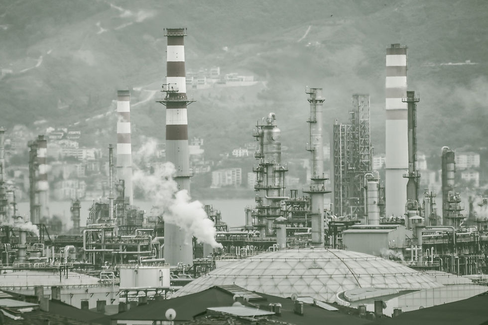 An oil refinery billows out plumes of white smoke as towers loom over a central processing plant. Image Credit: Wix