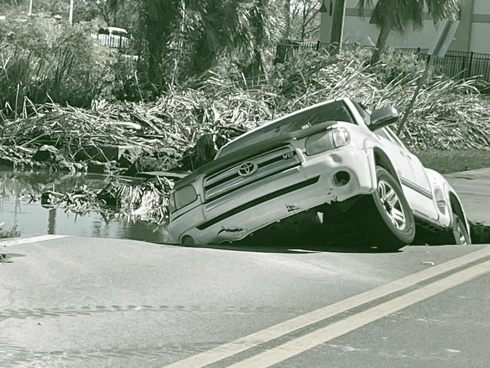 A damaged pickup truck rests askew within a sinkhole created by Hurricane Ian.