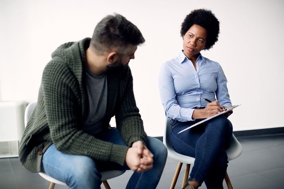 black-female-psychotherapist-taking-notes-while-talking-man-during-counselling.jpg