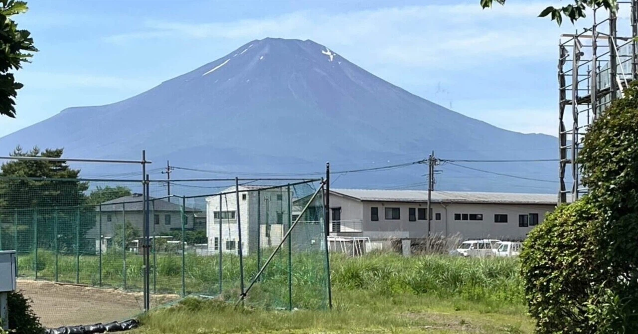 山中湖から見た富士山。手前には住宅とフェンスが写っています。