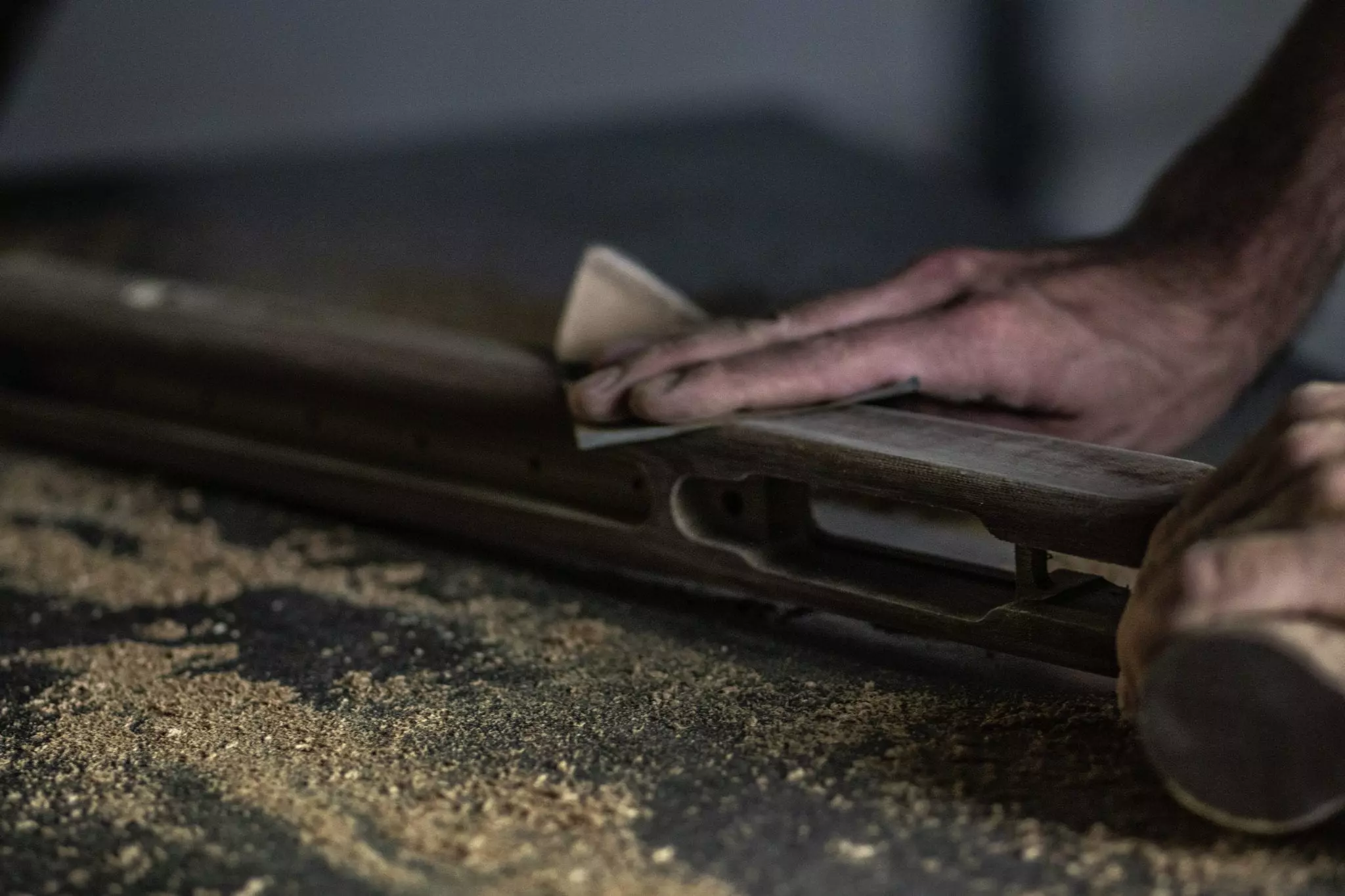 Craftsman carefully sanding rifle stock
