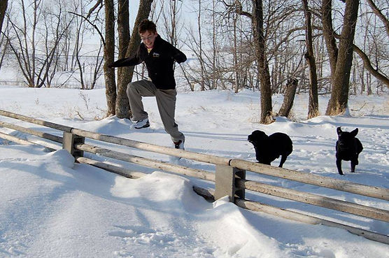 young man teaching dogs to jump fence in south dakota snow