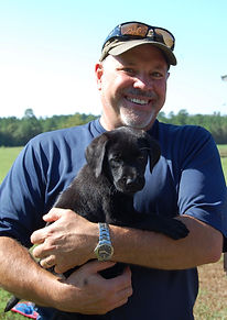 Happy man holding his black british lab puppy from Tallgrass Kennels