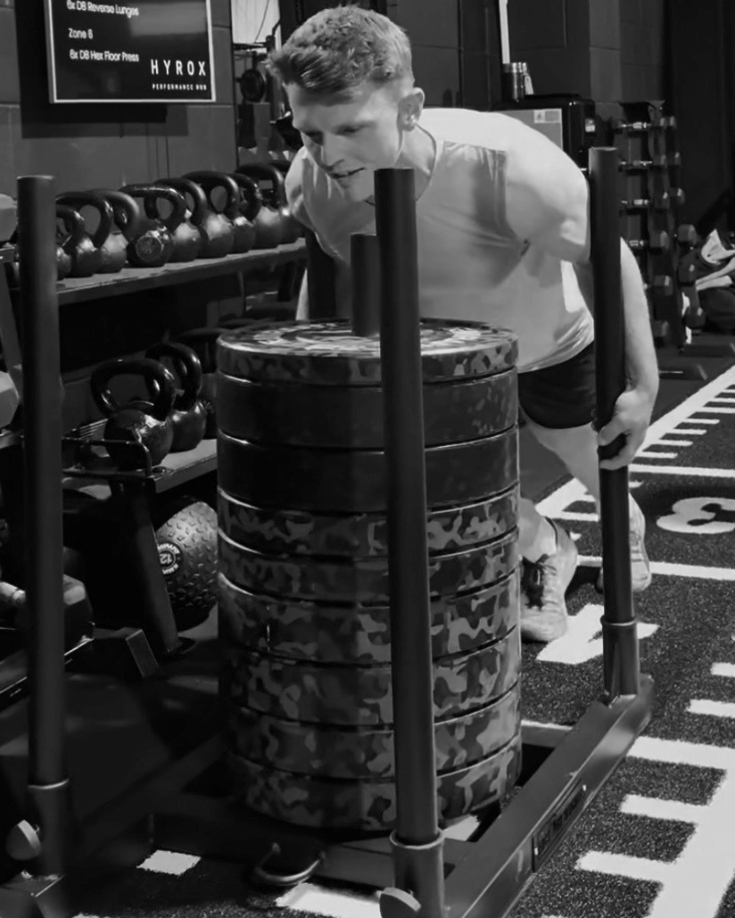 Member pushing a weighted sled at Shaded Fitness