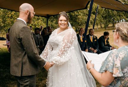 Bride and groom holding hands with Anne Matthew Celebrant during ceremony