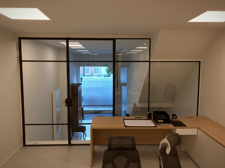 scheidingswand en deur uit gezwart massief staal en bezet met glas