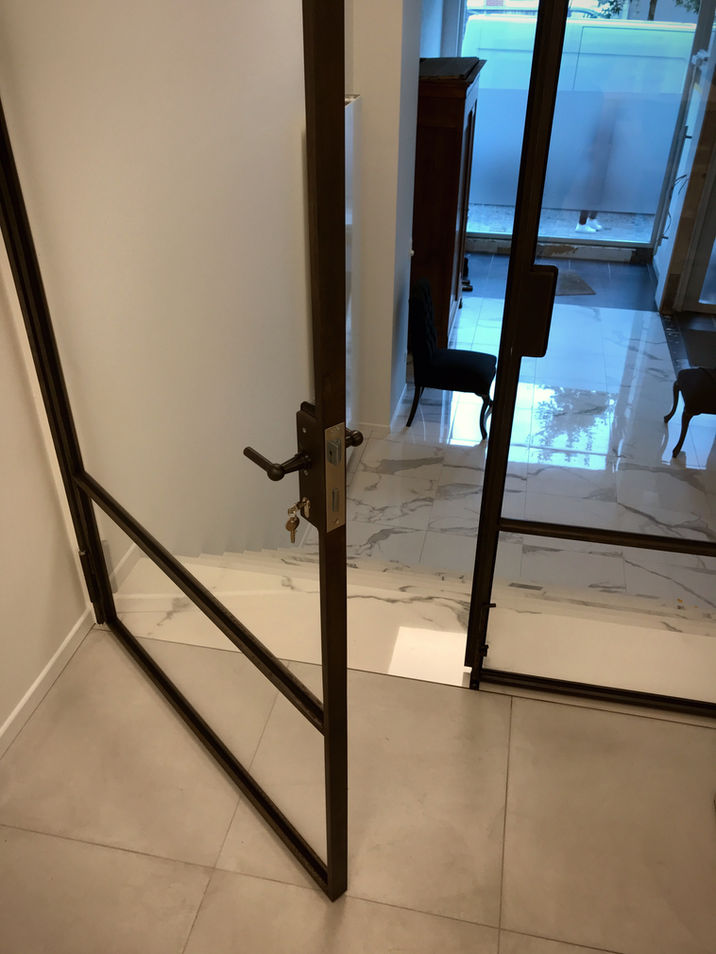 scheidingswand en deur uit gezwart massief staal en bezet met glas