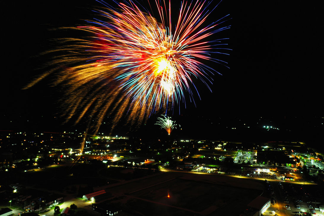 Multicolor fireworks show above cityscape at night.