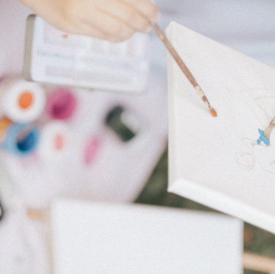 Close-up of a woman's hands using a paintbrush and watercolour palette to create a personal journal entry.
