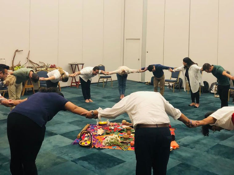 A team holding hands and bowing together towards the altar in the centre