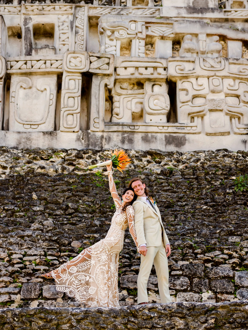 Bride and groom in front of the carved facade of a Mayan temple in Belize