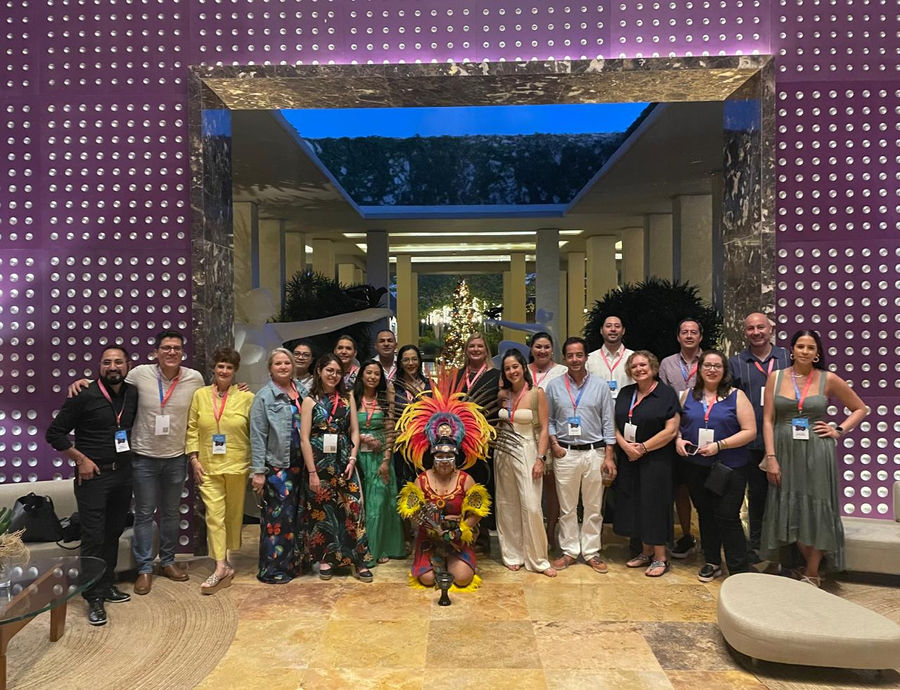 A corporate group gathered around a kneeling dancer in a hotel lobby after the welcome