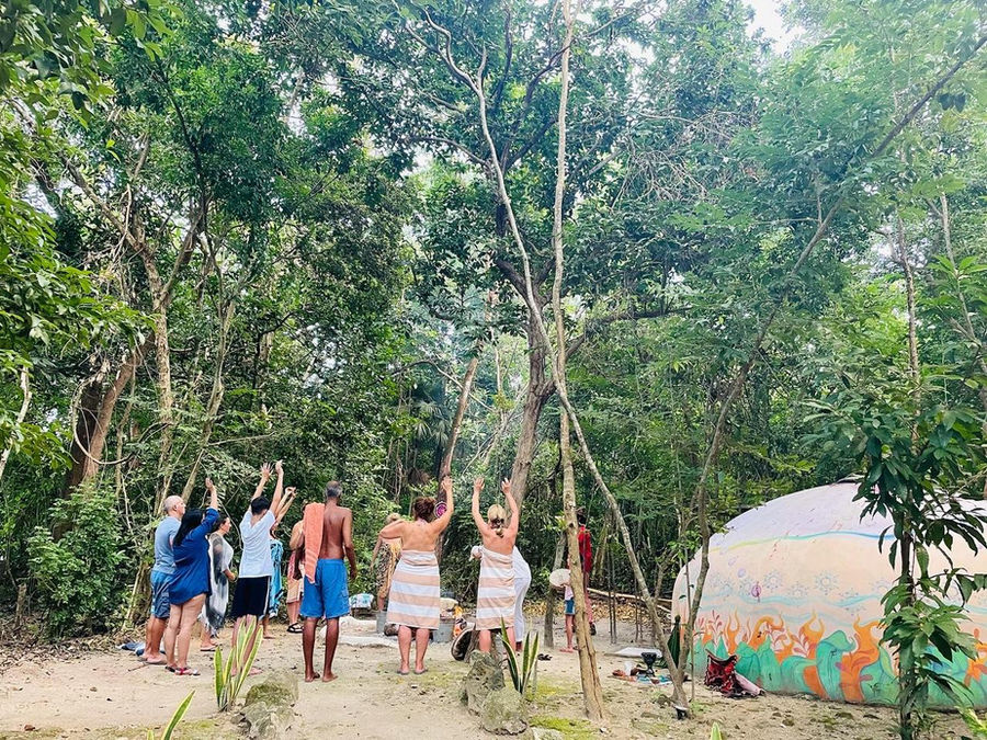 Personas con las manos arriba antes de entrar al temazcal, en medio de la selva
