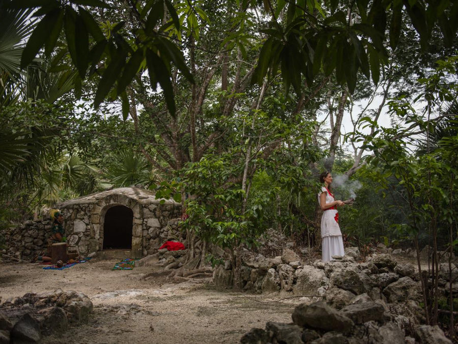 Sahumadora con el sahumerio humeante esperando afuera del temazcal