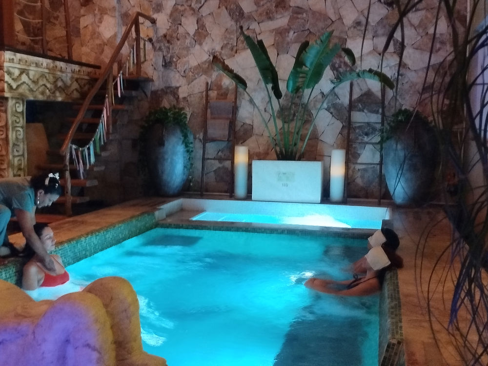 Personas en la alberca de hidroterapia de noche, con luz azul y una terapeuta al lado