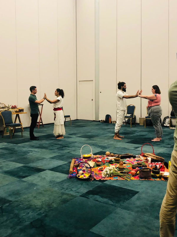 Two pairs of colleagues facing each other with their palms together, during an activity around the altar