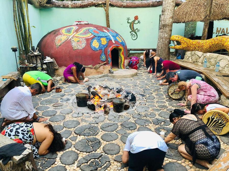 Círculo de personas de rodillas alrededor del fuego antes de entrar al temazcal