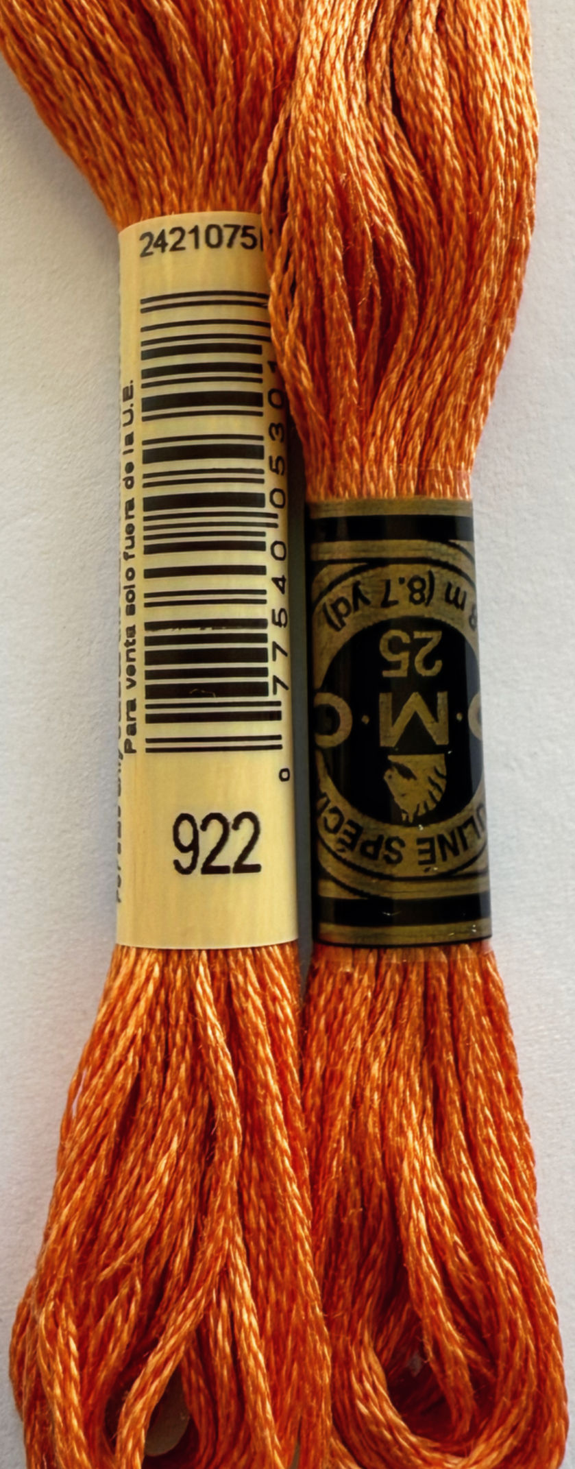 Orange DMC floss 922, with labels, close-up view of embroidery thread for crafts.