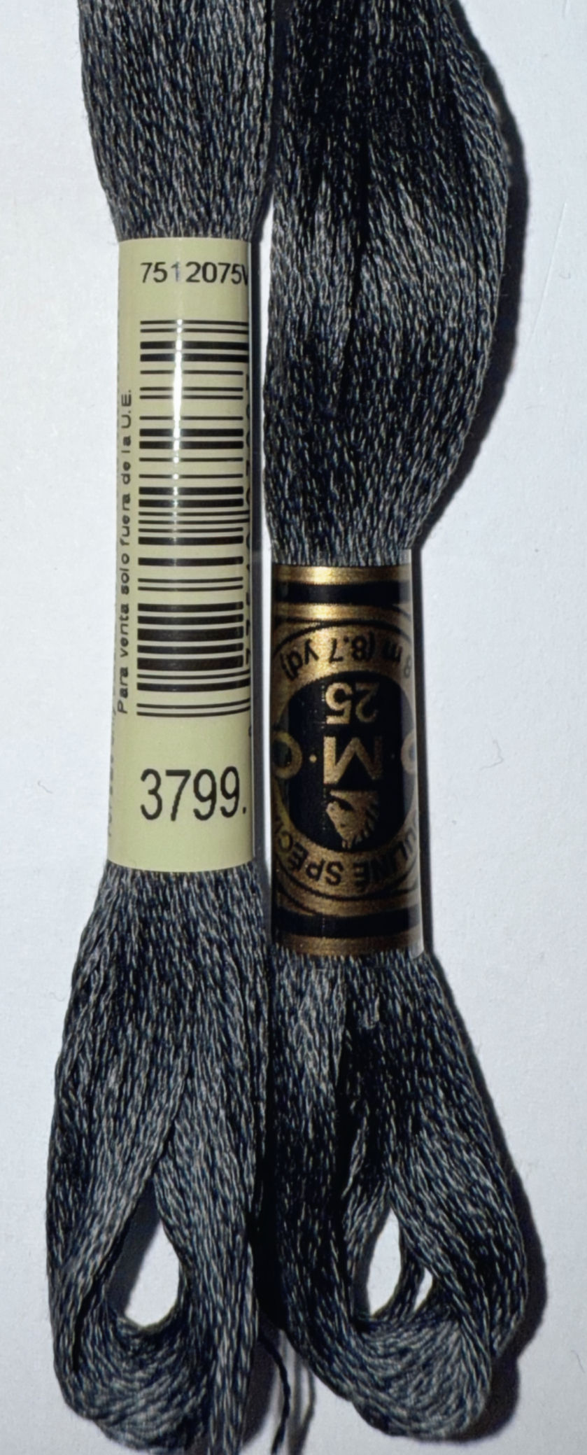 Two DMC embroidery floss spools with 3799 and M-C 25 labels shown close up.