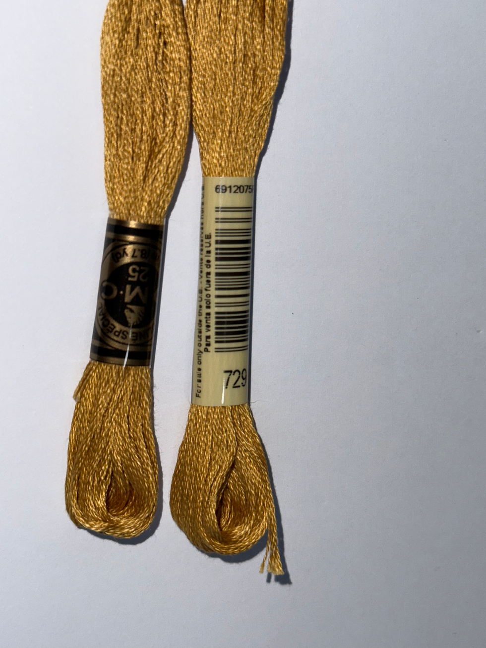 Two gold DMC thread skeins with white barcode label and 728 text.