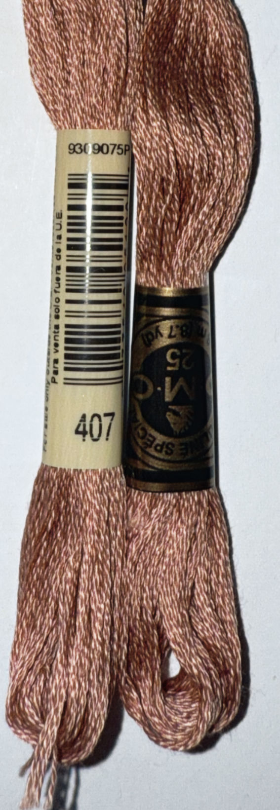 Two spools of DMC embroidery floss with visible text including 407 and brand name.
