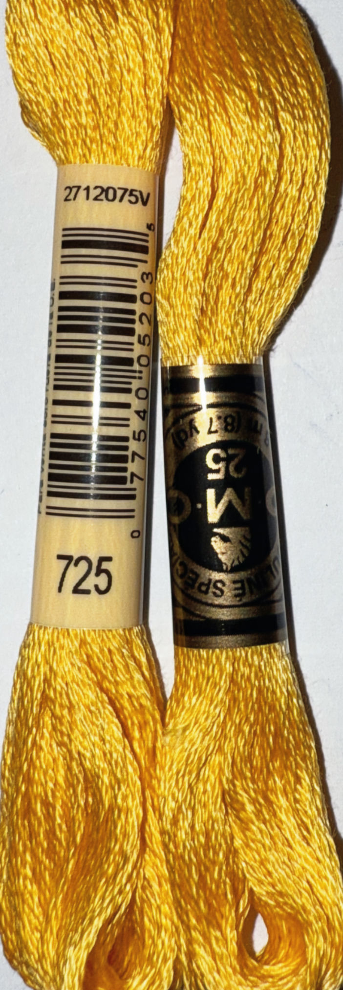DMC Floss 725 and barcode label on yellow thread skein with text.