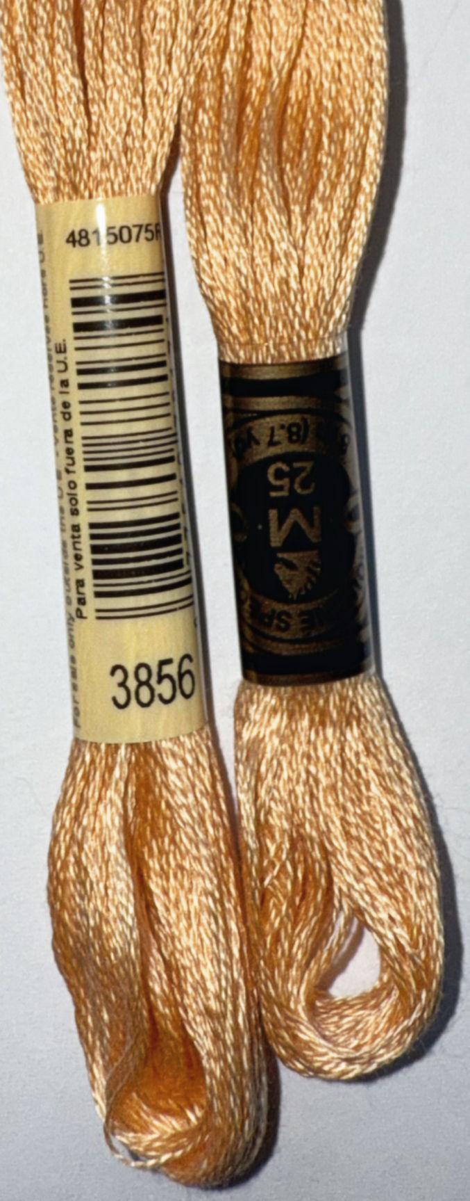 Two DMC floss skeins with the numbers 3856 and M25, gold threads.
