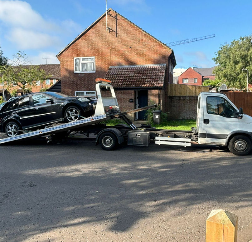 A picture of a car being unloaded from a truck.  