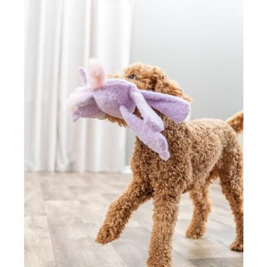 Un chiot endormi calé contre sa peluche licorne Trixie dans son panier