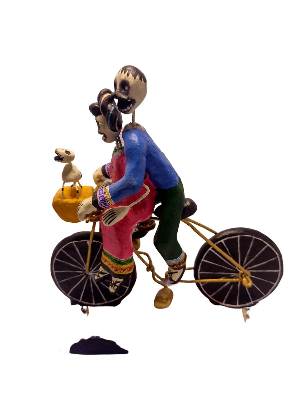 Escultura mexicana de calaveras en bicicleta vista de perfil, con detalles coloridos