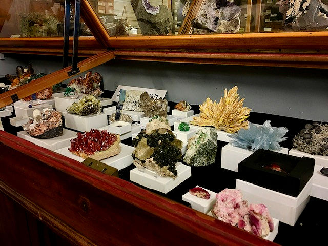 Colourful mineral specimens displayed in a historic glass-fronted cabinet at the Natural History Museum in London