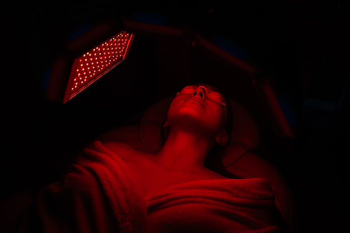 Relaxed woman receiving red light therapy facial treatment at Club Bed RLT