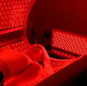 Woman receiving red light therapy treatment inside advanced wellness machine