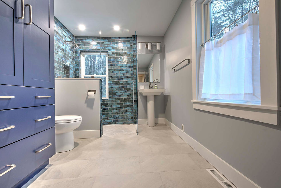 Modern bathroom with blue cabinetry, glass shower, and tiled accent wall.