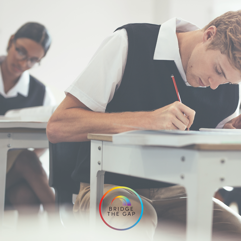 A boy with head down and pencil in his hand writing on an exam paper, a girl can be seen in the background doing the same.