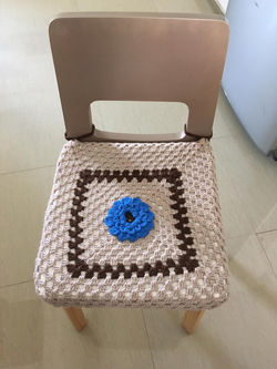 cojin tejido con detalle de flor azul