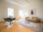 Bright living and dining area with sofa, round dining table and armchairs in the PREMIUM SUITE N°304 in the Erlenbad Resort, with parquet flooring, built-in wardrobes and large windows.