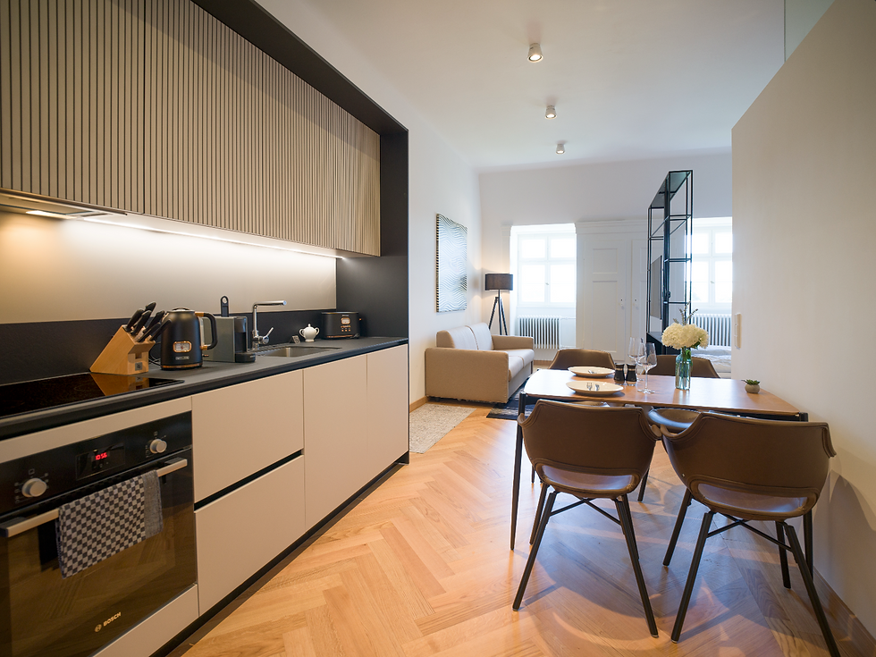 Suite lumineuse avec kitchenette moderne, grande table à manger et espace salon/chambre attenant, le tout dans un agencement ouvert.