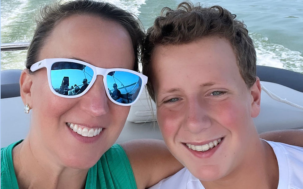 Mom in sunglasses and son sit in the back of a motor boat smiling. Image courtesy of Dr. Julie Sweeney.