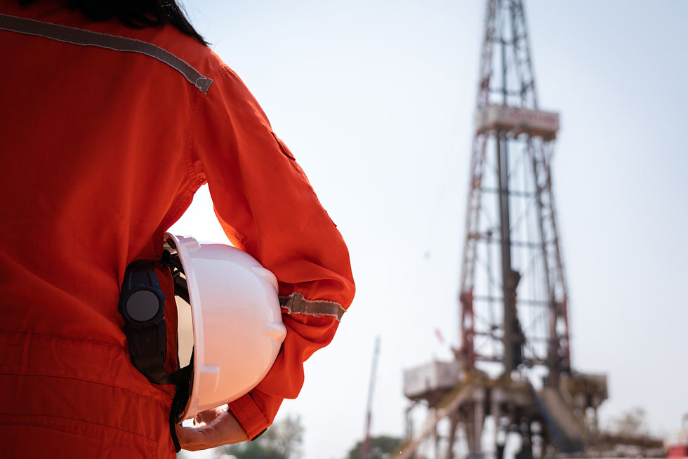 A worker is holding safety hardhat or helmet with blurred background of drilling rig