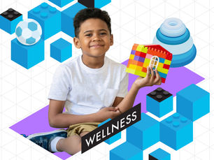 Smiling boy holds a colorful block house amid blue cubes; WELLNESS text on purple shape in a bright geometric background.