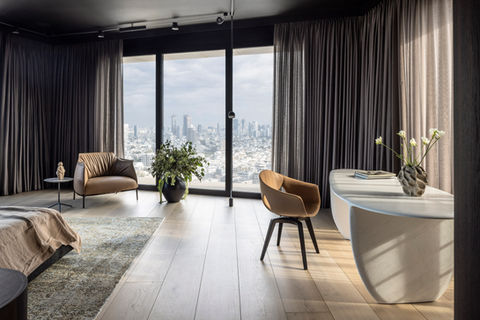 Elegant bedroom with city view, two chairs and desk. Anna Amiel Textile.