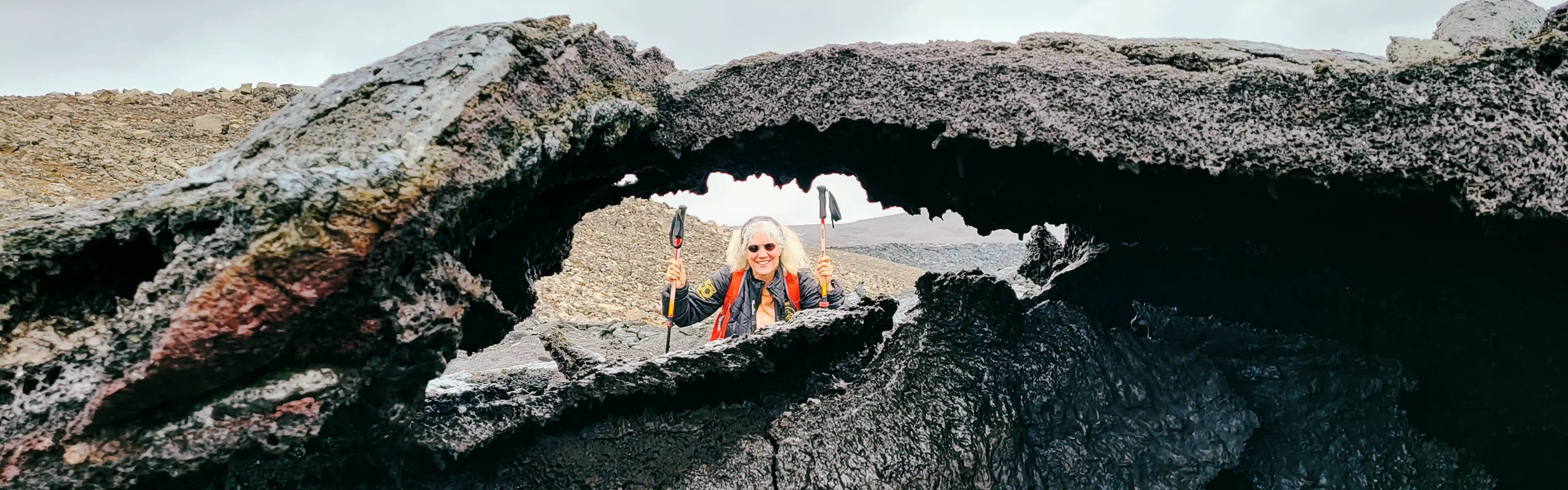 A woman hiking at Fagradalsfjall Volcano in Iceland, and a lava rock hole is visible..webp